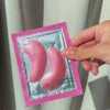 A woman unboxes Australian Bodycare's Vitamin B12 eye masks, removes the protective film, and gently places the pink patches beneath her eyes, smoothing them comfortably into place.